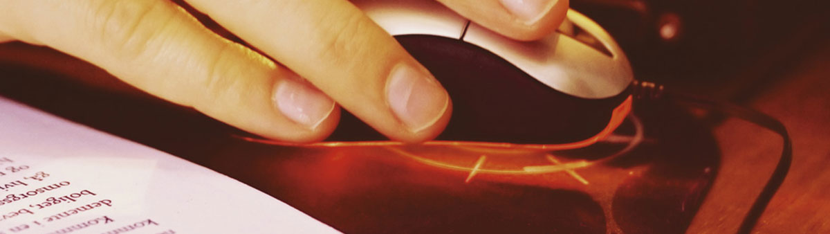 A person operating a computer mouse next to a book